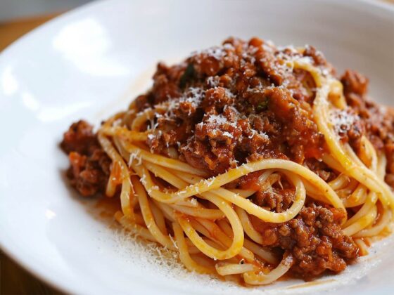 Spaghetti bolognese posypane tartym parmezanem, podane na talerzu