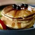 Pancakes podane z syropem klonowym, porzeczkami i nektarynką na talerzu