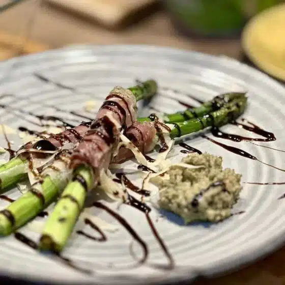 Szparagi z piekarnika w szynce parmeńskiej, podane z pesto orzechowym