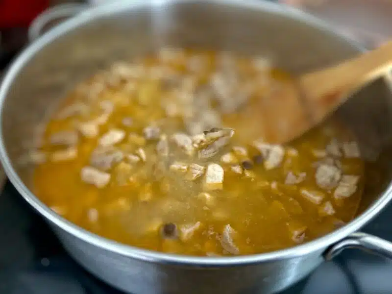 Gulasz wieprzowy w sosie własnym z zielonym groszkiem w trakcie gotowania w garnku