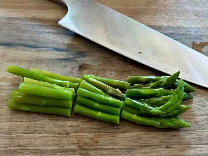 Pokrojone szparagi na drewnianej desce do krojenia