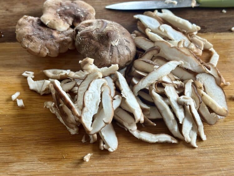 Grzyby shiitake pokrojone w plastry na drewnianej desce